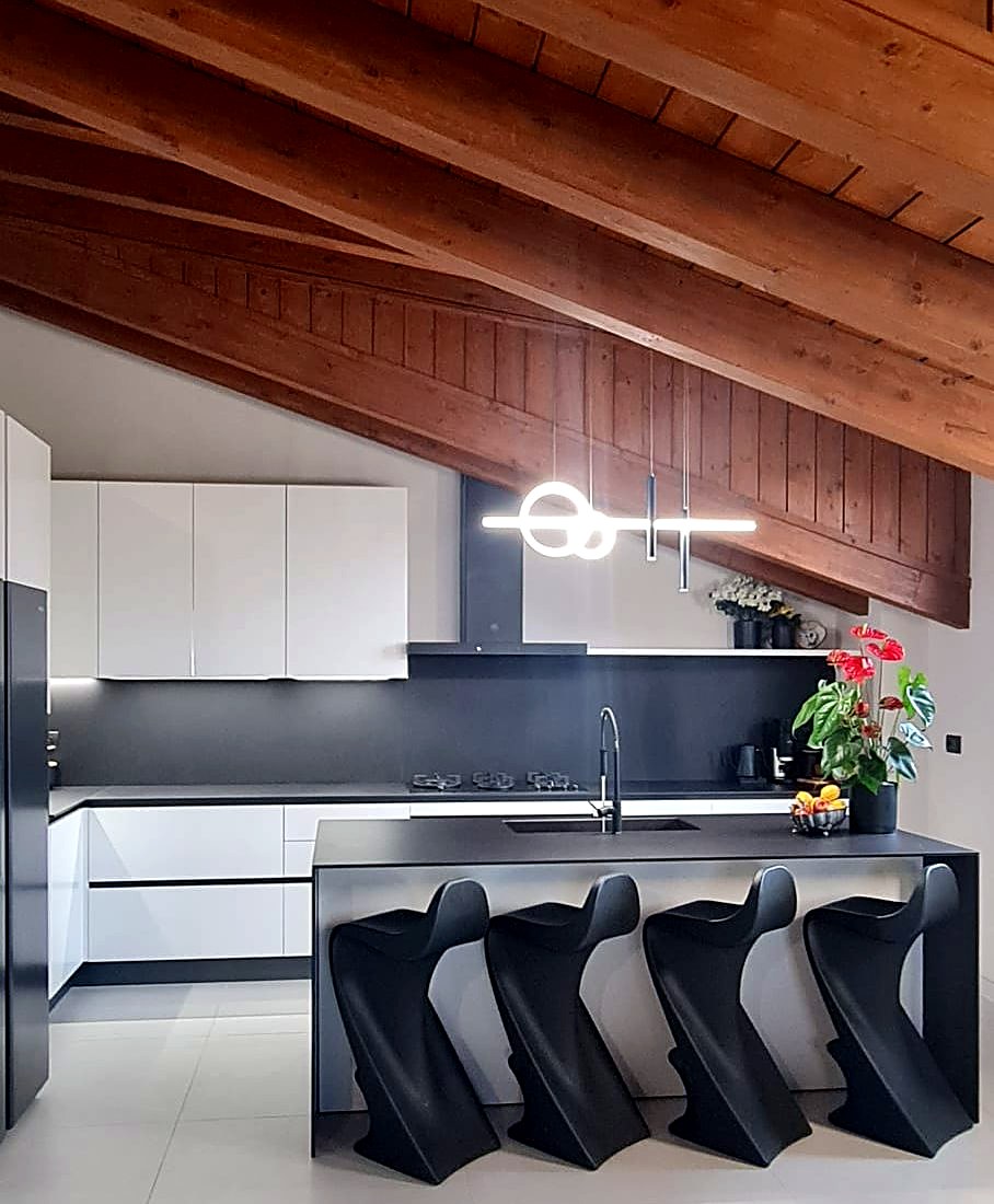 Attico con cucina su misura, isola in nero e travi in legno a vista